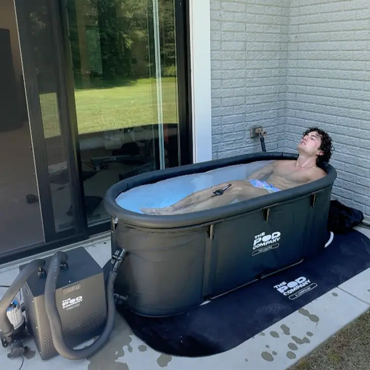 Person relaxing in a portable hot tub outside a house.